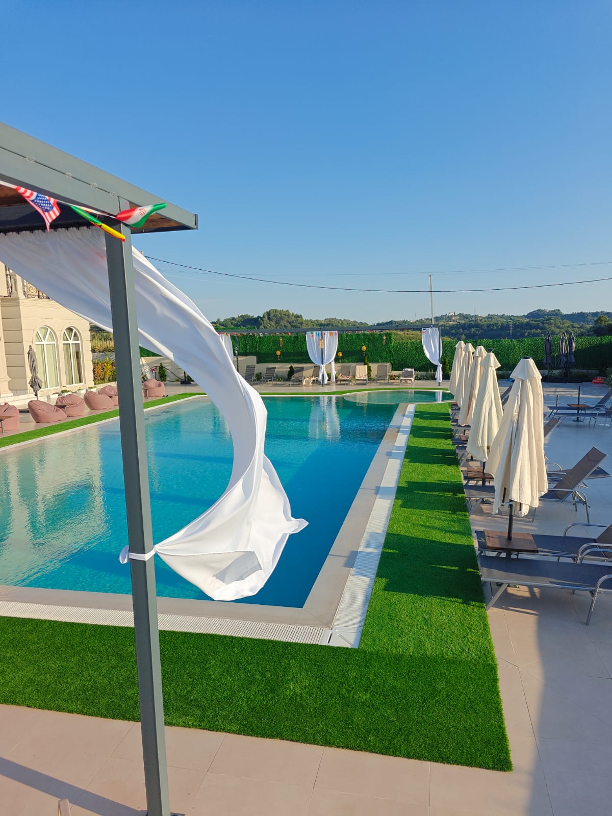 Piscina di giorno con tenda bianca al vento e lettini